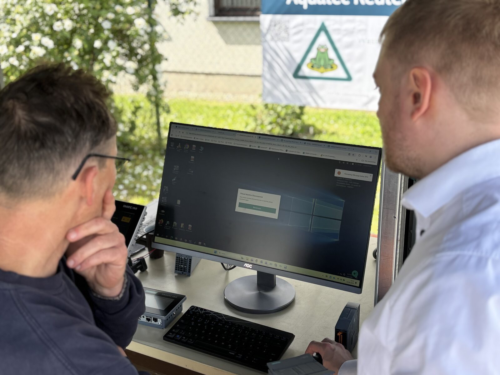 Teilnehmer am Demo-Monitor vor dem Aquatec-Reuter-Banner